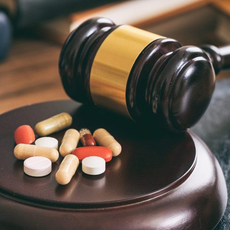 Law gavel and colorful pills on a wooden desk, dark background