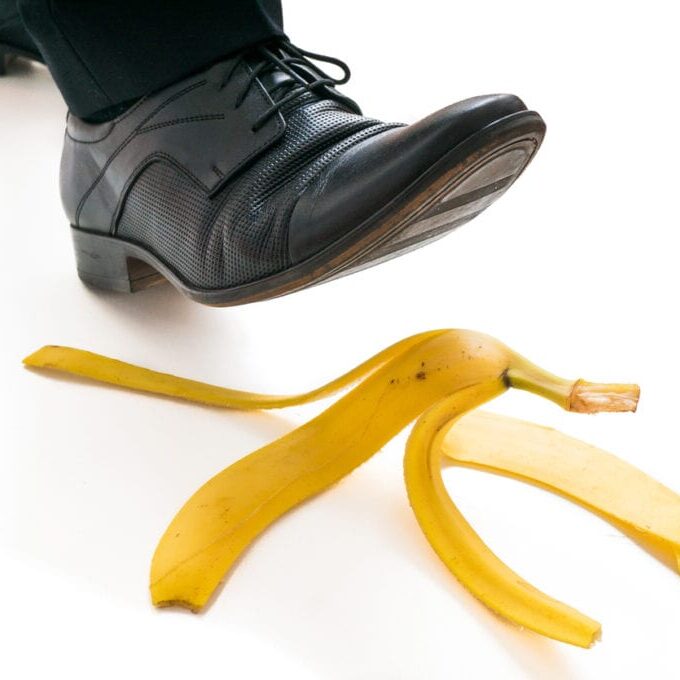 Walking businessman is going to slip on banana peel.